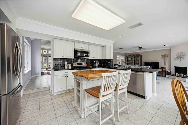16019 Juniper Grove Dr, Houston, TX 77084 - kitchen with appliances with stainless steel finishes, a peninsula, plenty of natural light, ornamental molding, and backsplash