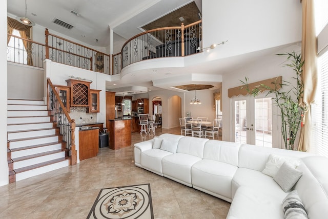 16206 Lobo Ln, Spring, TX 77379 - living area featuring arched walkways, a high ceiling, stairway, healthy amount of natural light, and french doors