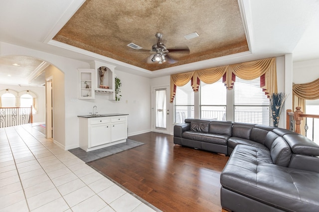 16206 Lobo Ln, Spring, TX 77379 - living room with a tray ceiling, arched walkways, dark wood-type flooring, ceiling fan, and bar