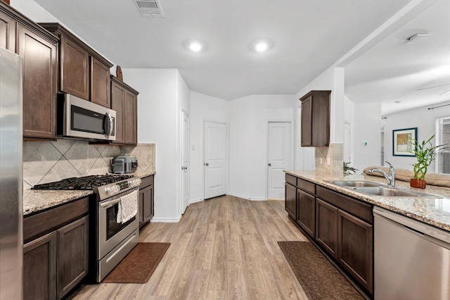 19018 Cicerone Ct, New Caney, TX 77357 - kitchen featuring appliances with stainless steel finishes, a sink, dark brown cabinetry, and decorative backsplash