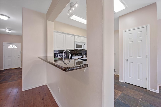 16315 Redbud Berry Ln, Cypress, TX 77433 - kitchen with white microwave, white cabinets, dark stone countertops, stove, and tasteful backsplash