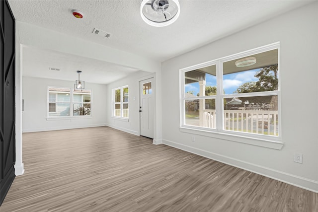 3910 Cetti St, Houston, TX 77009 - unfurnished living room with wood finished floors, baseboards, and a textured ceiling