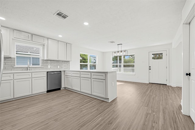 3910 Cetti St, Houston, TX 77009 - kitchen with dishwasher, light wood-style flooring, light countertops, a peninsula, and a sink