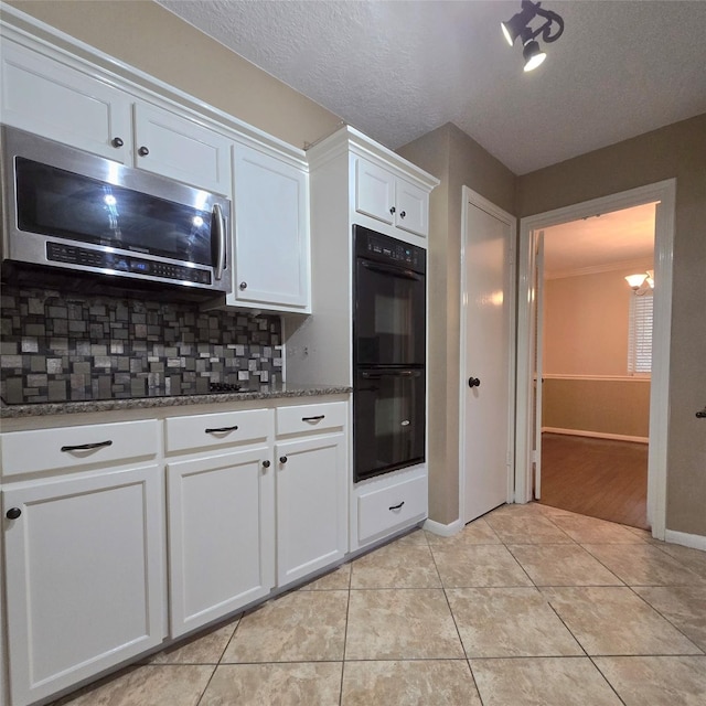 20339 Acapulco Cove Dr, Humble, TX 77346 - kitchen with stainless steel microwave, decorative backsplash, light tile patterned flooring, white cabinetry, and stone counters