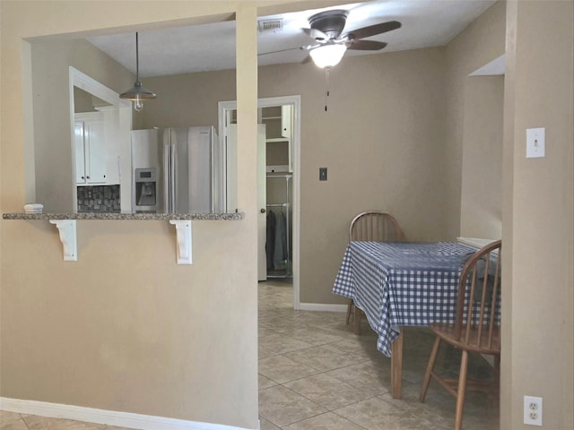 20339 Acapulco Cove Dr, Humble, TX 77346 - kitchen featuring stainless steel refrigerator with ice dispenser, ceiling fan, a breakfast bar, light tile patterned floors, and stone counters