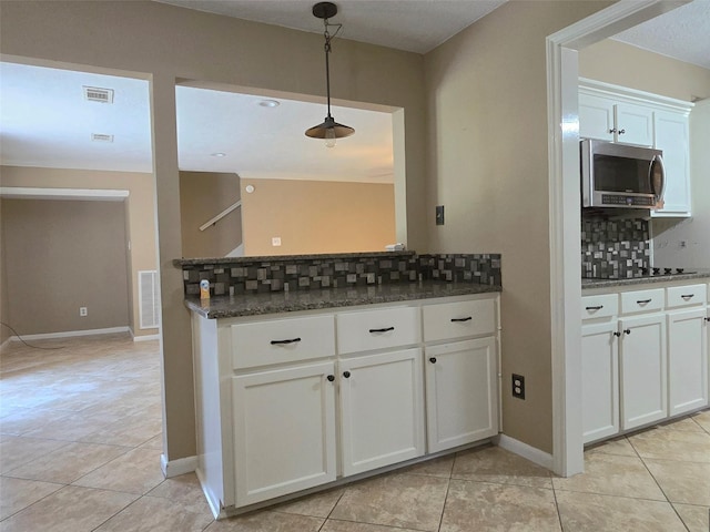 20339 Acapulco Cove Dr, Humble, TX 77346 - kitchen with stainless steel microwave, decorative backsplash, light tile patterned floors, and white cabinets