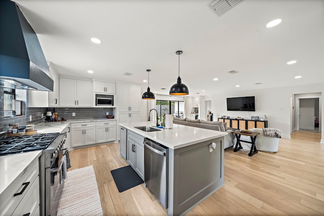 1902 Knoboak Cir, Houston, TX 77080 - kitchen featuring a sink, appliances with stainless steel finishes, wall chimney range hood, tasteful backsplash, and light wood finished floors