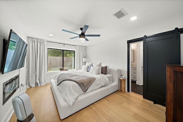 1902 Knoboak Cir, Houston, TX 77080 - bedroom featuring a barn door, light wood-style floors, recessed lighting, and ceiling fan