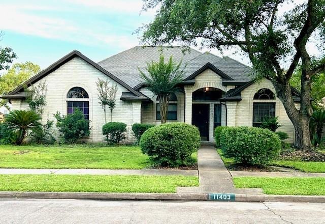 11403 High Bridge Ct, Houston, TX 77065 - french country style house featuring brick siding, a front lawn, and roof with shingles