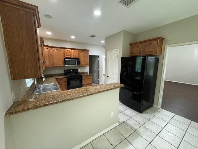 2232 Stableridge Dr, Conroe, TX 77384 - kitchen with black appliances, a sink, a peninsula, light tile patterned flooring, and brown cabinets