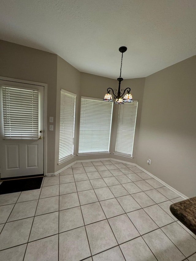2232 Stableridge Dr, Conroe, TX 77384 - unfurnished dining area with a chandelier, light tile patterned floors, and baseboards