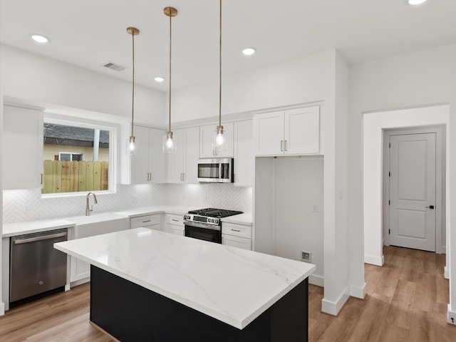 7729 Ave J Unit A, Houston, TX 77012 - kitchen with stainless steel appliances, a sink, decorative backsplash, light stone counters, and white cabinets