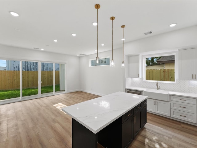 7729 Ave J Unit A, Houston, TX 77012 - kitchen with a sink, backsplash, white cabinets, recessed lighting, and a kitchen island