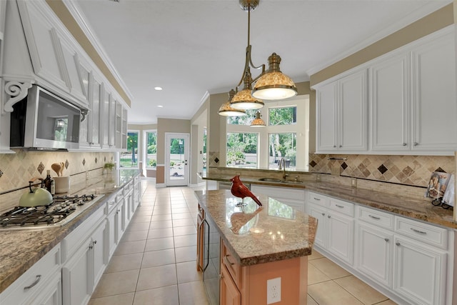 14806 Cantwell Bnd, Cypress, TX 77429 - kitchen featuring stainless steel appliances, a center island, tasteful backsplash, light tile patterned flooring, and crown molding