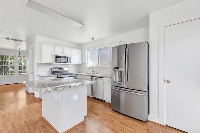 26881 Manor Crest Ct, Kingwood, TX 77339 - kitchen with stainless steel appliances, plenty of natural light, white cabinets, and light wood-style floors