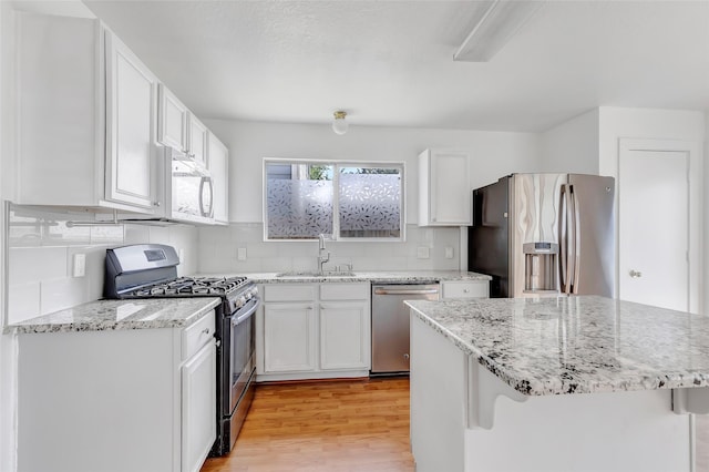 26881 Manor Crest Ct, Kingwood, TX 77339 - kitchen featuring stainless steel appliances, a sink, light wood-type flooring, and white cabinetry