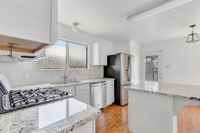 26881 Manor Crest Ct, Kingwood, TX 77339 - kitchen featuring appliances with stainless steel finishes, a sink, tasteful backsplash, white cabinetry, and light wood-style flooring