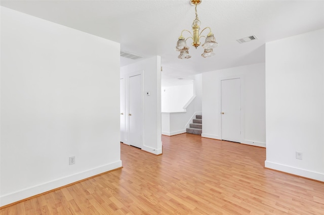 26881 Manor Crest Ct, Kingwood, TX 77339 - empty room with a chandelier, light wood-style flooring, stairway, and baseboards
