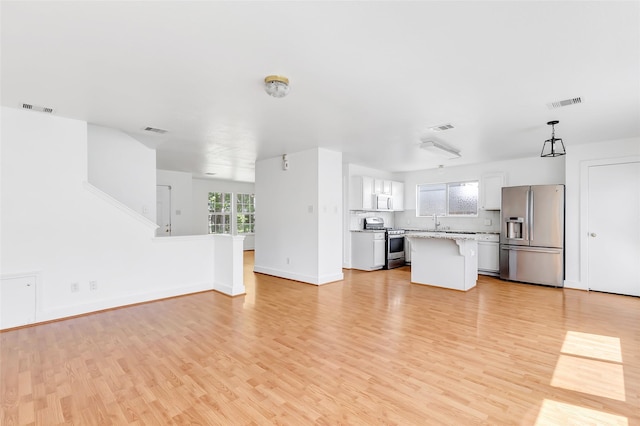 26881 Manor Crest Ct, Kingwood, TX 77339 - unfurnished living room with light wood-style floors, baseboards, and a sink