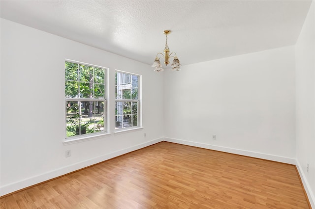 26881 Manor Crest Ct, Kingwood, TX 77339 - empty room with a chandelier, light wood-style flooring, and baseboards