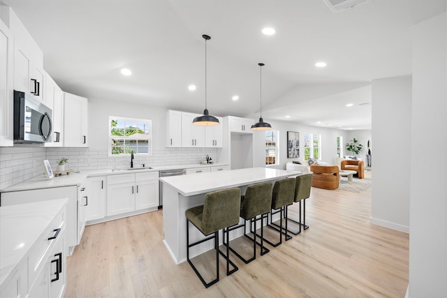 1310 E 34th St, Houston, TX 77022 - kitchen with appliances with stainless steel finishes, a sink, a breakfast bar, tasteful backsplash, and light wood-style flooring