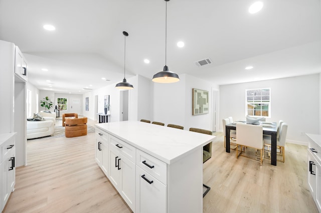 1310 E 34th St, Houston, TX 77022 - kitchen featuring light wood-style flooring, a center island, a kitchen breakfast bar, decorative light fixtures, and open floor plan