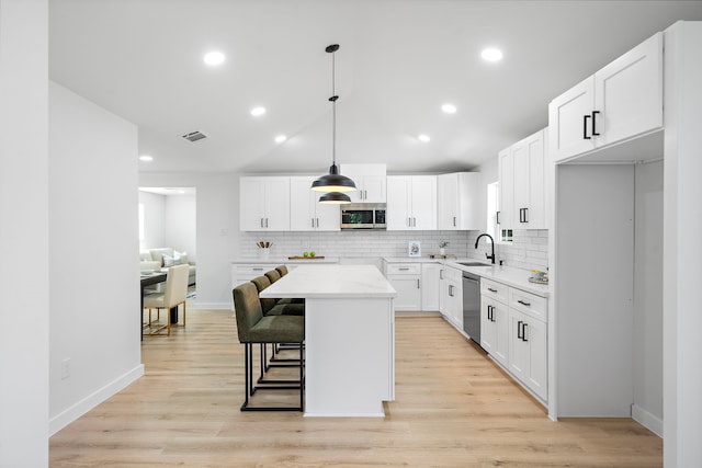1310 E 34th St, Houston, TX 77022 - kitchen with appliances with stainless steel finishes, a sink, backsplash, a kitchen island, and white cabinetry
