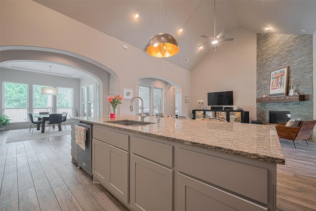 13707 Rivendell Crest Ln, Cypress, TX 77429 - kitchen featuring arched walkways, light wood-type flooring, light stone countertops, open floor plan, and high vaulted ceiling