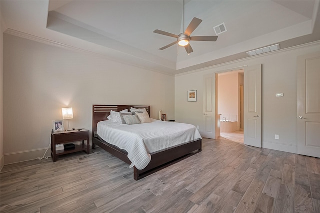 13707 Rivendell Crest Ln, Cypress, TX 77429 - bedroom featuring a raised ceiling, wood finished floors, ceiling fan, and ensuite bathroom