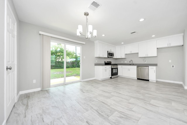 5911 Southurst St, Houston, TX 77033 - kitchen with stainless steel appliances, a chandelier, baseboards, white cabinets, and recessed lighting