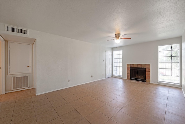 12500 Sandpiper Dr Unit 5, Houston, TX 77035 - unfurnished living room with ceiling fan, a tiled fireplace, baseboards, tile patterned floors, and a textured ceiling