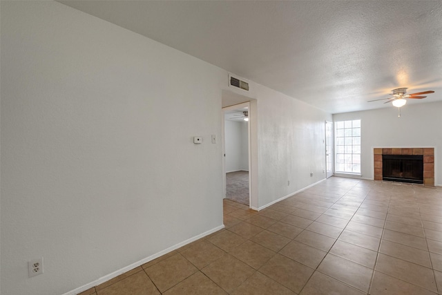 12500 Sandpiper Dr Unit 5, Houston, TX 77035 - unfurnished living room with a ceiling fan, tile patterned flooring, a tile fireplace, baseboards, and a textured ceiling