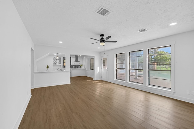16218 Coral Bay St, Crosby, TX 77532 - unfurnished living room with wood finished floors, ceiling fan, a textured ceiling, baseboards, and recessed lighting