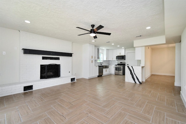 1003 Crescent Blvd, Cleveland, TX 77327 - unfurnished living room featuring baseboards, ceiling fan, a textured ceiling, a fireplace, and recessed lighting