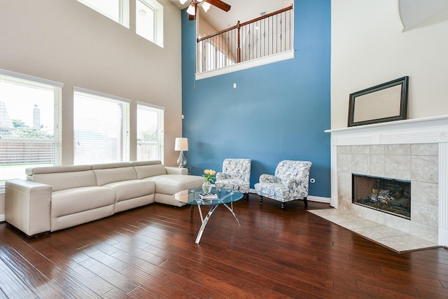 26706 Grey Swan Dr, Katy, TX 77494 - living room featuring a ceiling fan, a high ceiling, healthy amount of natural light, a tiled fireplace, and hardwood / wood-style floors