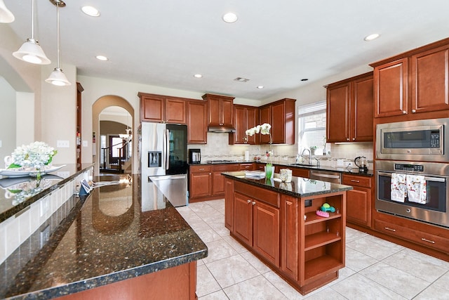 26706 Grey Swan Dr, Katy, TX 77494 - kitchen with appliances with stainless steel finishes, a center island, arched walkways, under cabinet range hood, and open shelves