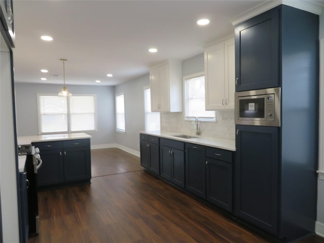 1103 Jocelyn St, Houston, TX 77023 - kitchen featuring stainless steel appliances, dark wood-style flooring, light countertops, a sink, and baseboards