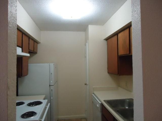 12500 Sandpiper Dr Unit 6, Houston, TX 77035 - kitchen featuring white appliances, a sink, under cabinet range hood, brown cabinets, and light countertops