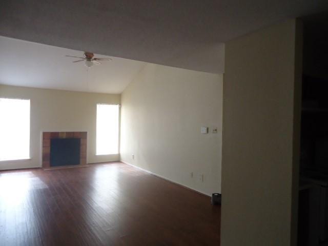 12500 Sandpiper Dr Unit 6, Houston, TX 77035 - unfurnished living room with a tiled fireplace, ceiling fan, healthy amount of natural light, vaulted ceiling, and wood finished floors