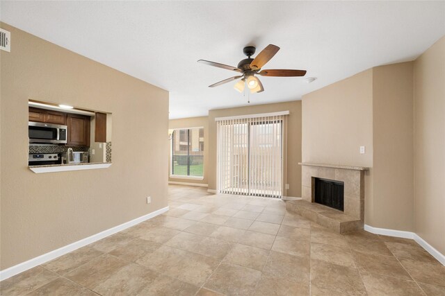 16111 Aspenglenn Dr Unit 803, Houston, TX 77084 - unfurnished living room with ceiling fan, a tiled fireplace, baseboards, and light tile patterned floors