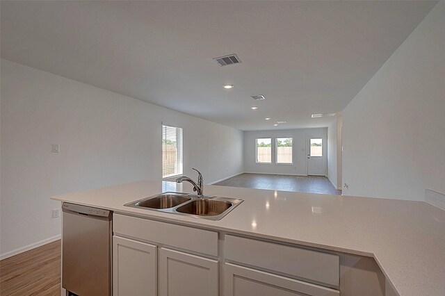 19915 Epirus Shores Dr, Hockley, TX 77447 - kitchen featuring stainless steel dishwasher, a sink, open floor plan, light wood-style flooring, and light countertops