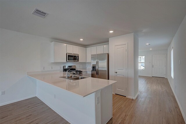 19915 Epirus Shores Dr, Hockley, TX 77447 - kitchen with stainless steel appliances, a sink, a peninsula, light wood-type flooring, and recessed lighting