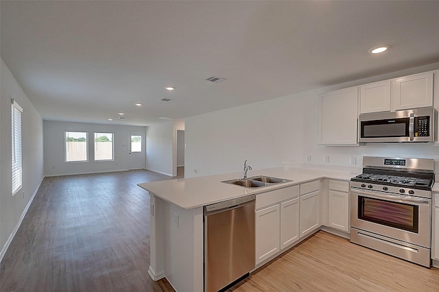19915 Epirus Shores Dr, Hockley, TX 77447 - kitchen with appliances with stainless steel finishes, a sink, light wood-style floors, a peninsula, and recessed lighting