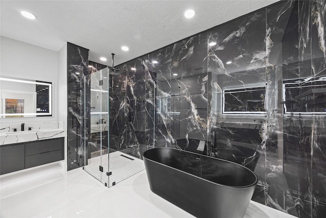 7827 Alamar Dr, Houston, TX 77095 - bathroom featuring recessed lighting, a marble finish shower, a soaking tub, vanity, and a textured ceiling