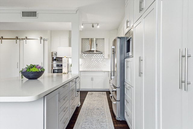 651 Bering Dr Unit 906, Houston, TX 77057 - kitchen with wall chimney range hood, appliances with stainless steel finishes, dark wood-style flooring, light countertops, and backsplash