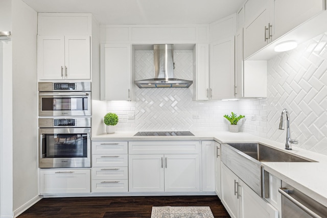 651 Bering Dr Unit 906, Houston, TX 77057 - kitchen with wall chimney range hood, stainless steel appliances, white cabinetry, tasteful backsplash, and light countertops