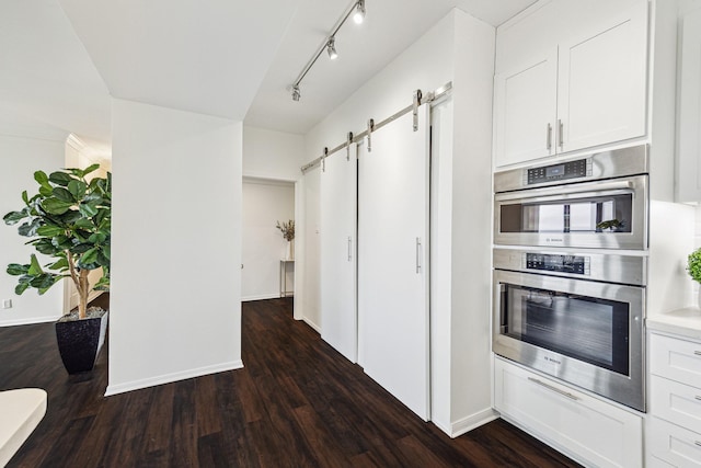 651 Bering Dr Unit 906, Houston, TX 77057 - kitchen featuring stainless steel double oven, a barn door, dark wood finished floors, baseboards, and white cabinetry