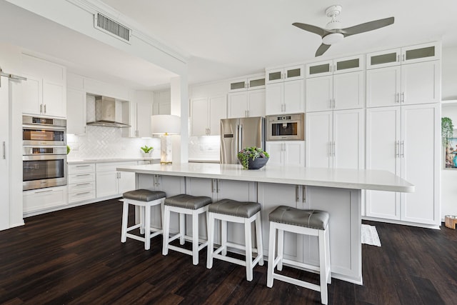 651 Bering Dr Unit 906, Houston, TX 77057 - kitchen with appliances with stainless steel finishes, wall chimney range hood, white cabinetry, light countertops, and decorative backsplash