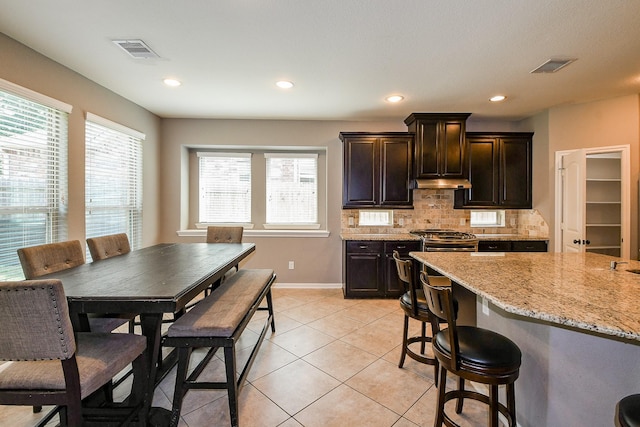 3544 Woods Estates Dr, Conroe, TX 77304 - kitchen featuring under cabinet range hood, baseboards, plenty of natural light, stainless steel range, and recessed lighting