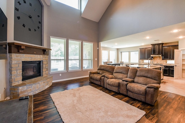 3544 Woods Estates Dr, Conroe, TX 77304 - living room with wood finished floors, a stone fireplace, a towering ceiling, baseboards, and recessed lighting